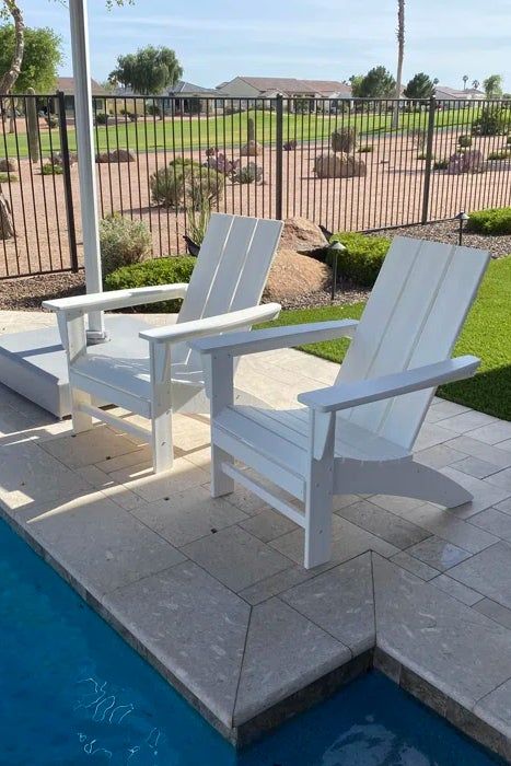 A reviewer's photo showing the Adirondack chairs in white, placed beside a pool.