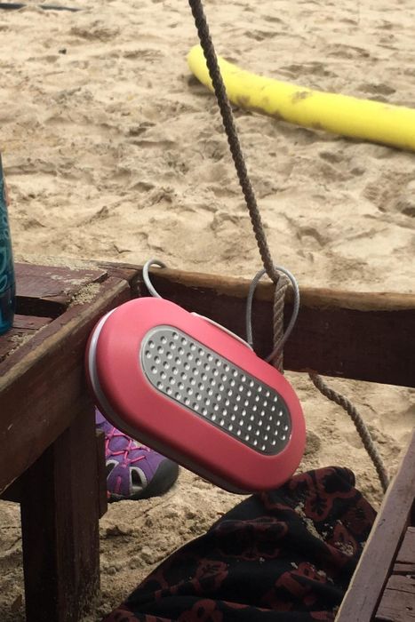 The reviewer's pink personal safe is securely attached to a beach chair, providing peace of mind while they enjoy the beach.