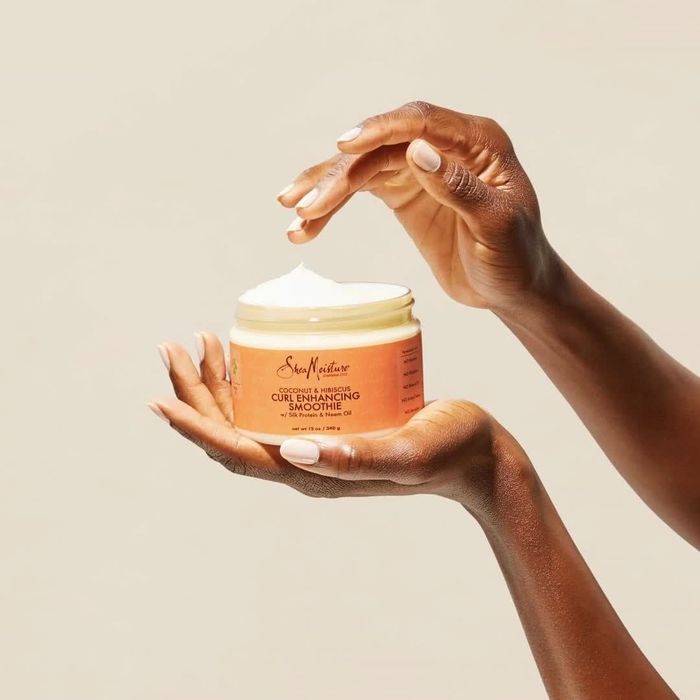 Two hands holding a tub of hair product