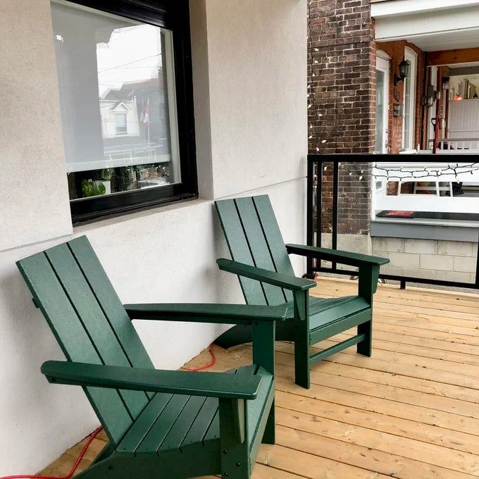 A reviewer's photo of the Adirondack chairs in green, positioned on a porch.