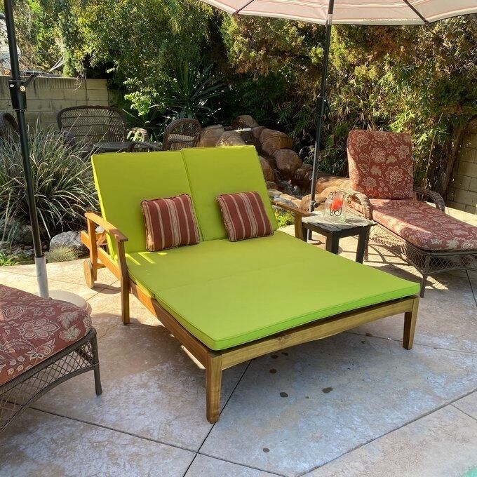 A set of outdoor furniture featuring a green cushioned lounge chair and a patio umbrella, ideal for a garden setting.