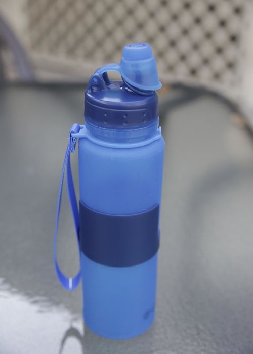 The reviewer presents the water bottle fully expanded and filled with water, ready for use.