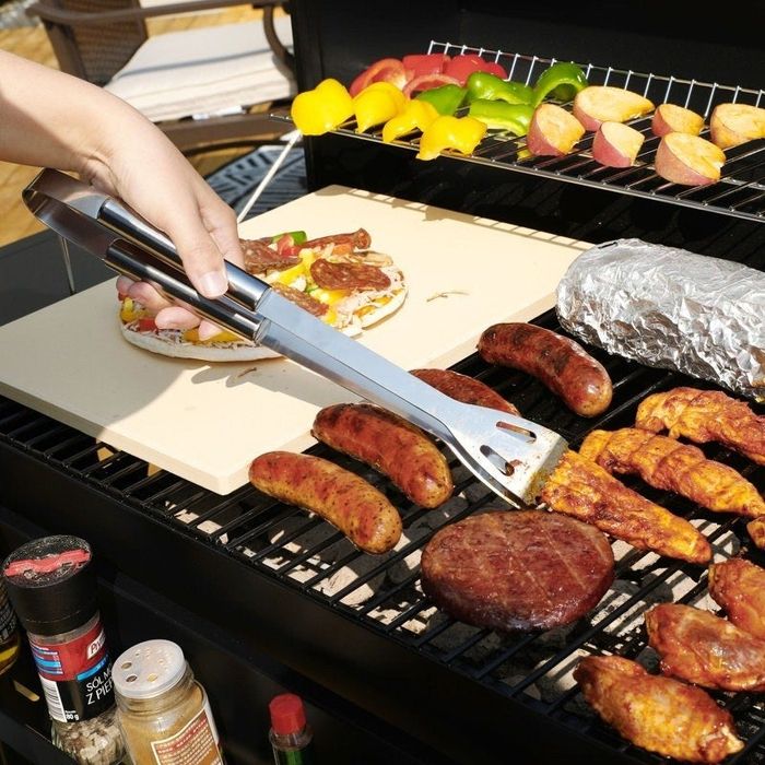 A model using the shiny silver tongs to expertly flip meat on a hot grill, showcasing the precision and quality of the grilling tools.