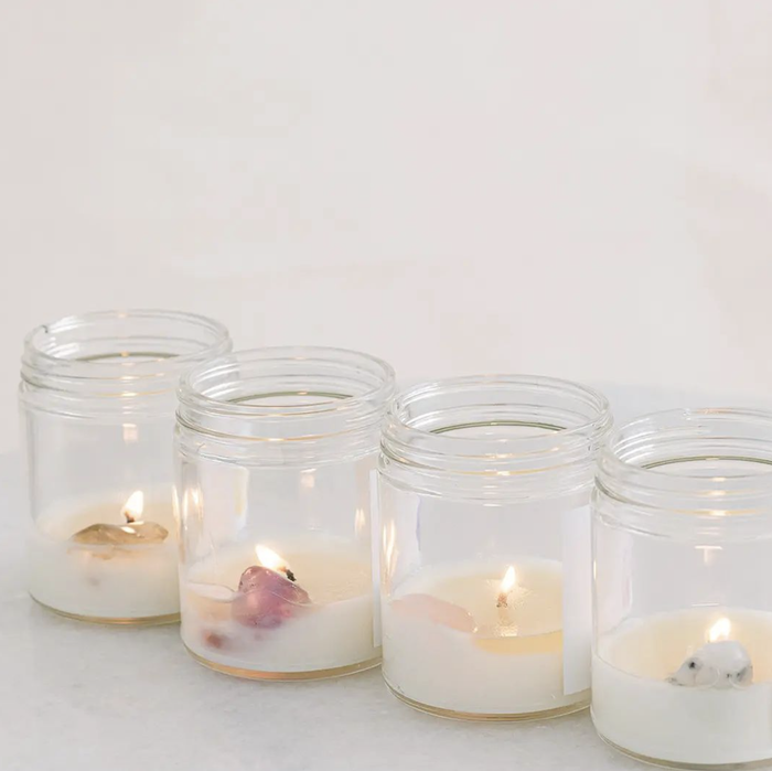 Four candles almost burned down to three-quarters, revealing the crystal hidden at the bottom of the jar.