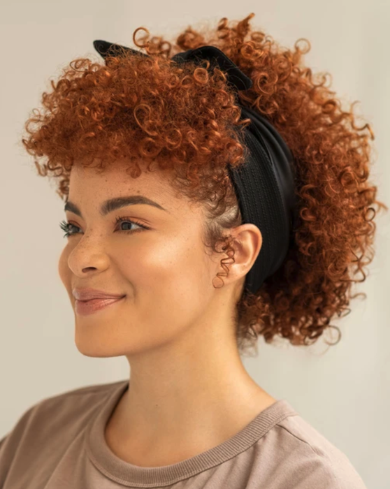 A model with curly hair wearing the bandie in black.