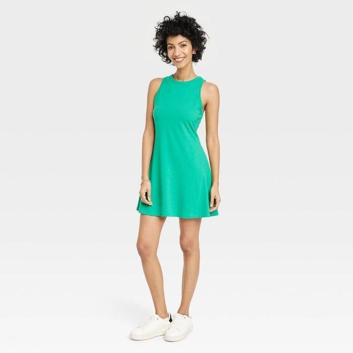 A model rocking a green dress paired with white sneakers