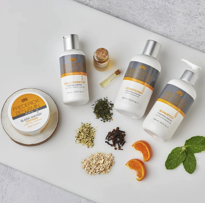 The four hair products, along with some of their key ingredients, arranged on a surface.