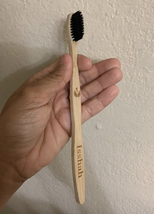 A reviewer is seen holding the bamboo toothbrush, showcasing its simple and elegant design.