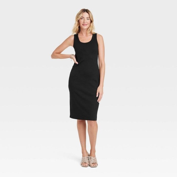 A model in a black dress paired with beige shoes