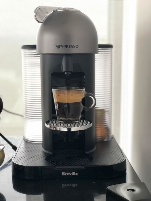 A reviewer's sleek grey coffee maker in action, brewing a rich espresso.