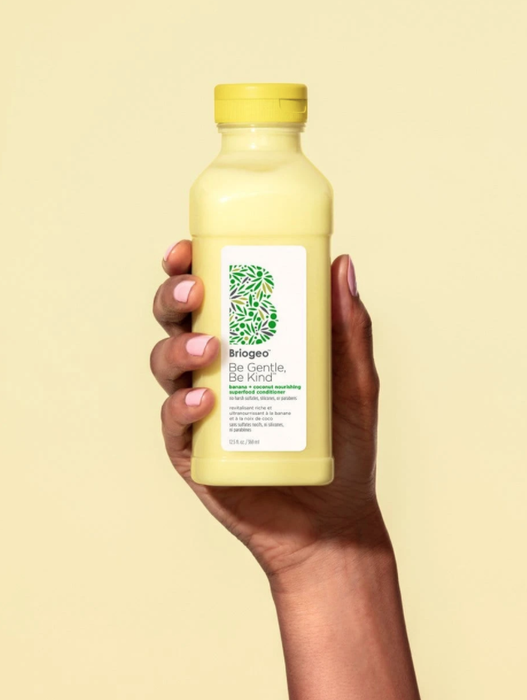 A hand holding the bottle of conditioner.