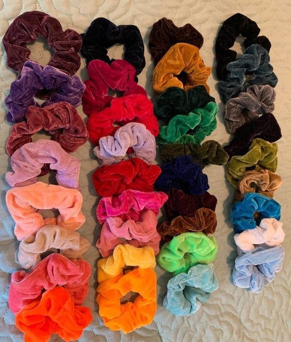 A reviewer showcases a vibrant collection of velvet scrunchies in various colors.