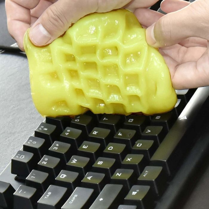 Someone using the cleaning gel on a computer keyboard