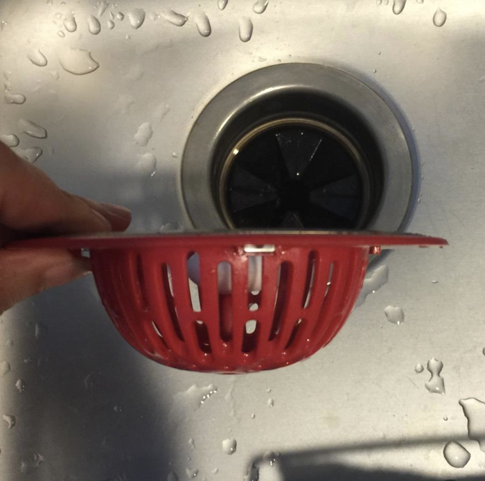Another photo of the red sink strainer, highlighting its cheerful rooster shape and utility.