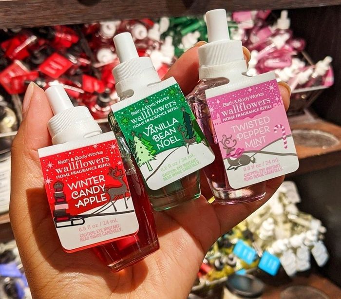 A hand holding three wallflower fragrance refills.