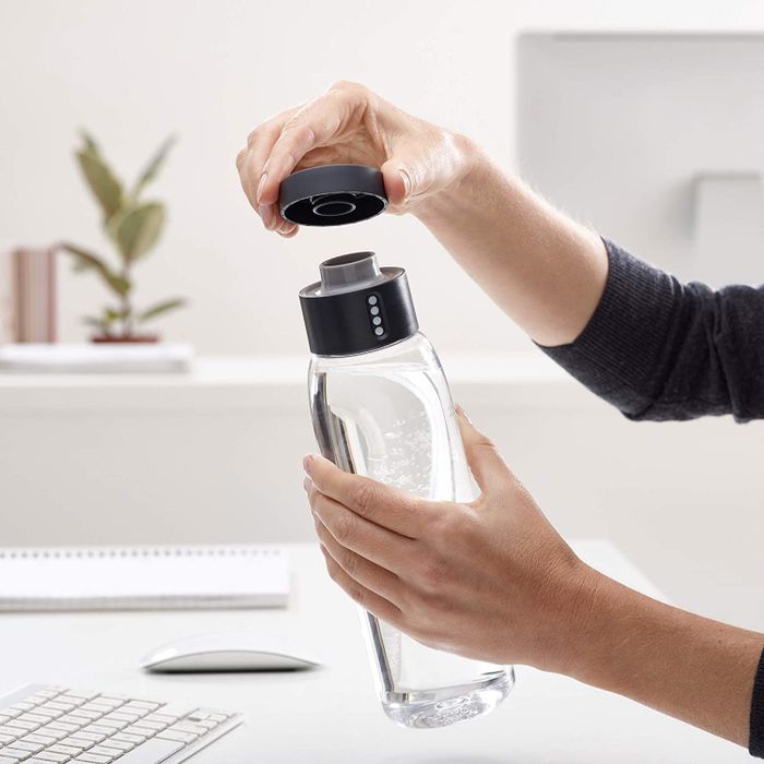 A model holding a clear water bottle with a black cap.