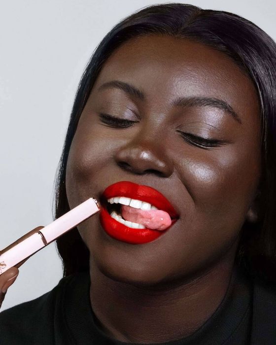 A woman applying a bold lipstick, demonstrating the makeup product for a shopping article.