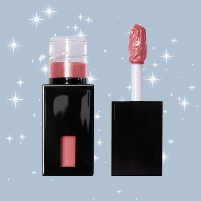 A shiny pink lip gloss tube with a wand, set against a glittery backdrop, showcased in a shopping feature.