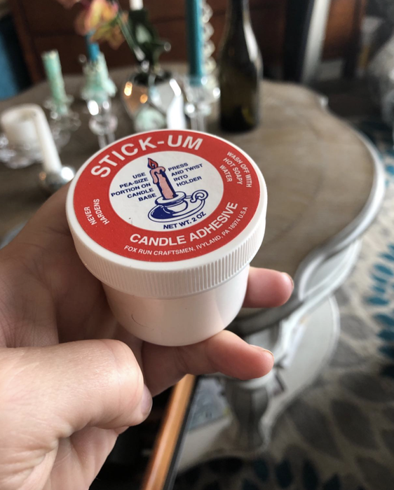 A reviewer holding a white jar of the adhesive product.