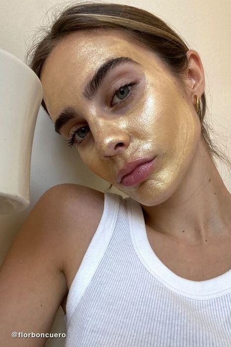 A model is seen wearing the gold mask, showcasing its application and luxurious appeal.
