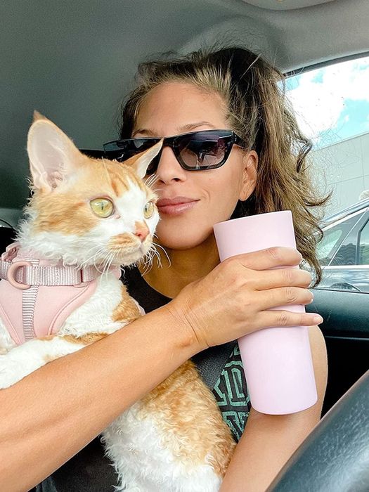 Reviewer holding her cat while gripping the iced coffee mug