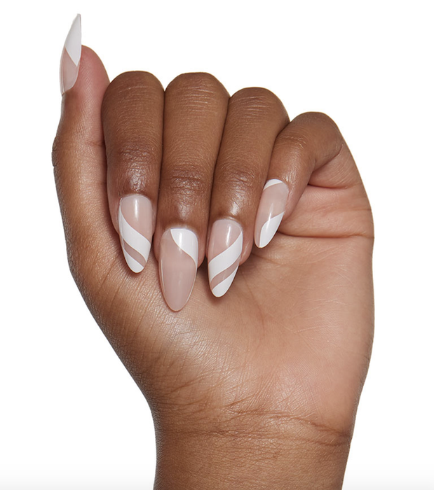 A hand adorned with nails featuring white stripes and negative space designs