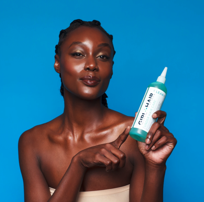 A model holding a bottle of the apple cider vinegar hair rinse.