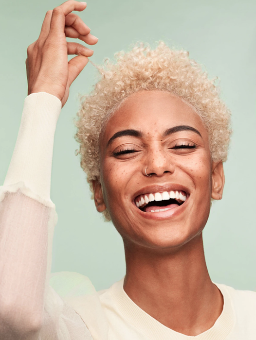A model with short, bleached curly hair.