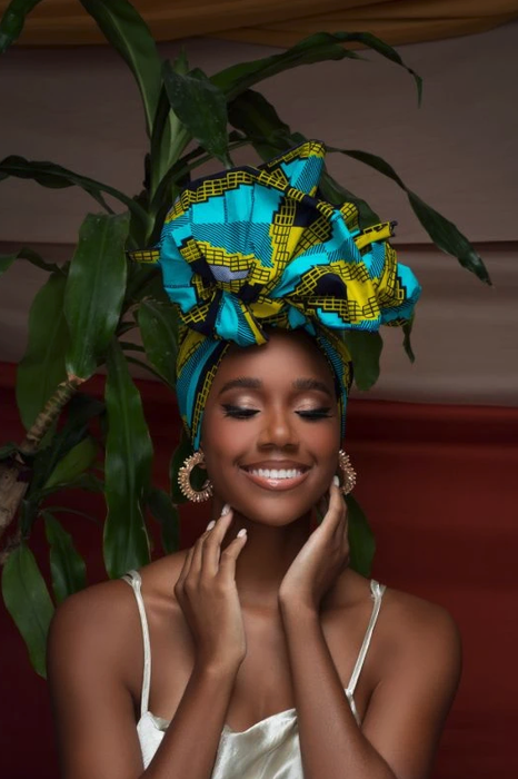 A model wearing a teal and blue head wrap, showcasing a stylish look.