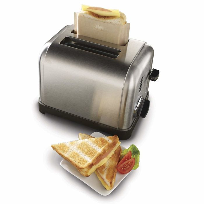 A grilled cheese sandwich alongside a toaster with another sandwich in the bag, ready to be toasted.