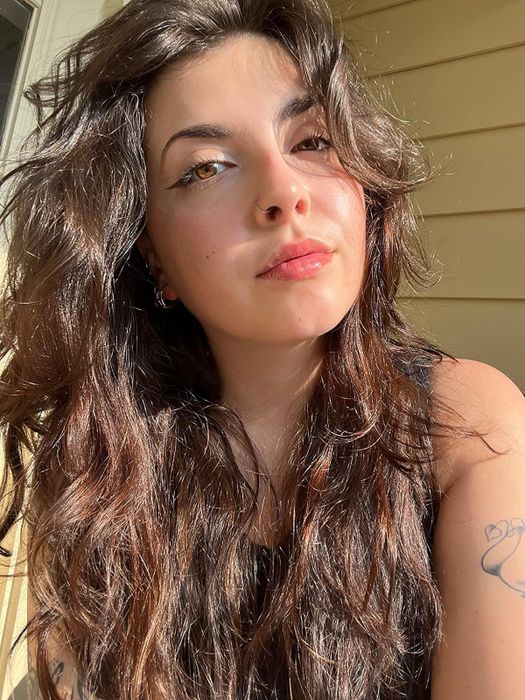 A reviewer taking a selfie with noticeably smooth, clear skin after using the moisturizer for some time.