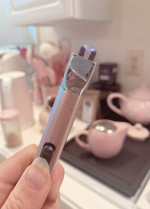 A rose gold electric lighter emitting a current of energy