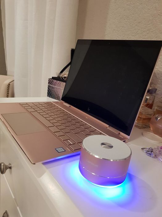 A reviewer demonstrating the small circular speaker next to a laptop
