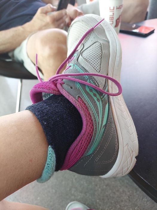 An ankle sock with a teal tab peeking over the heel of a running sneaker