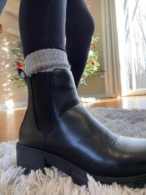 A reviewer rocking chic black ankle boots paired with gray socks