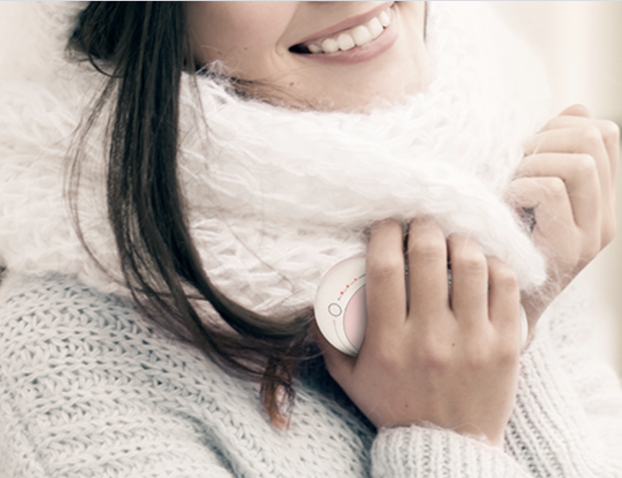 A model holding a pink hand warmer in their hand