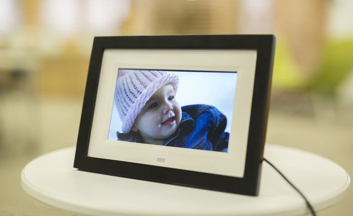 The frame connected to the wall, showing a picture of a baby on its screen