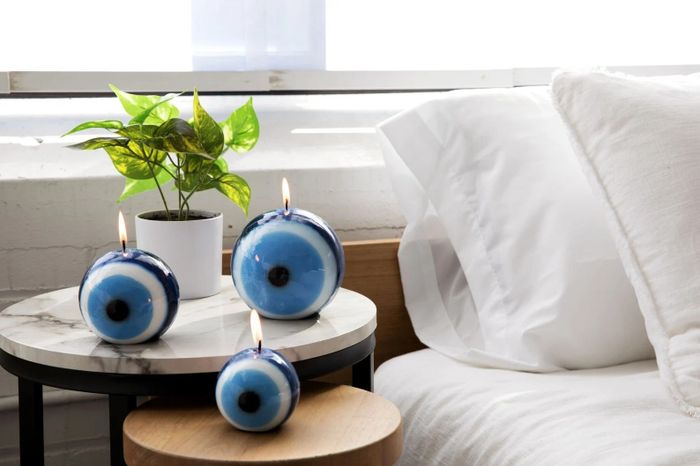 A group of lit evil eye candles in various sizes placed elegantly on a nightstand