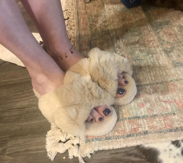 The reviewer is sporting some plush, camel-colored open-toe criss-cross slippers.