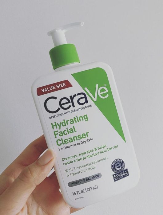 A person holding the green and white cleanser bottle
