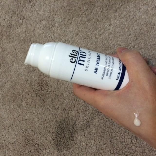 a reviewer holding a moisturizer bottle with some product on their hand