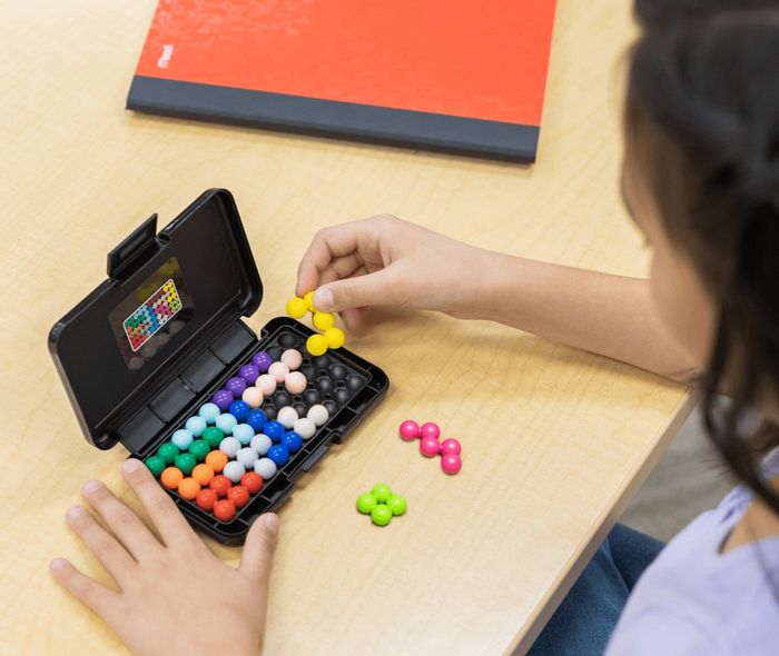 A person working on a brain teaser puzzle at a desk. The text reads,