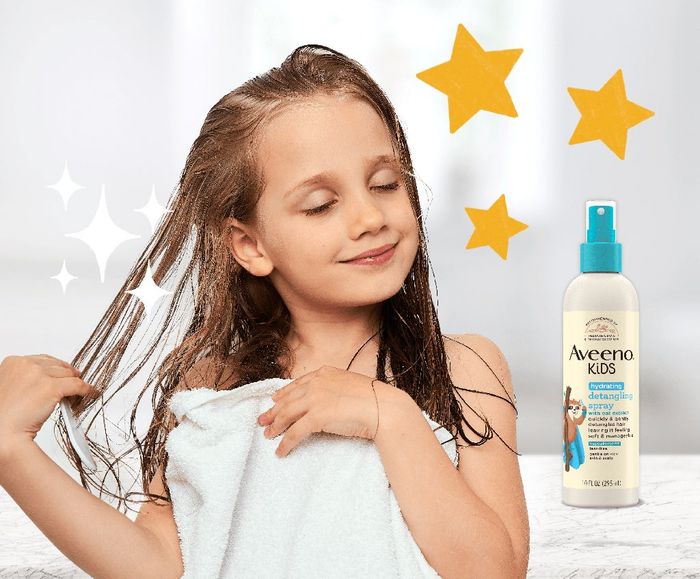 Child drying their hair with a towel next to Aveeno Kids Detangling Spray