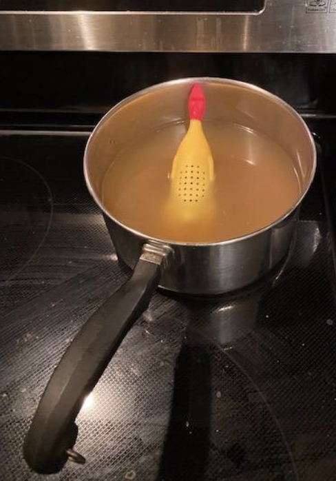 A reviewer's snapshot of a chicken herb infuser placed in a pot filled with water.