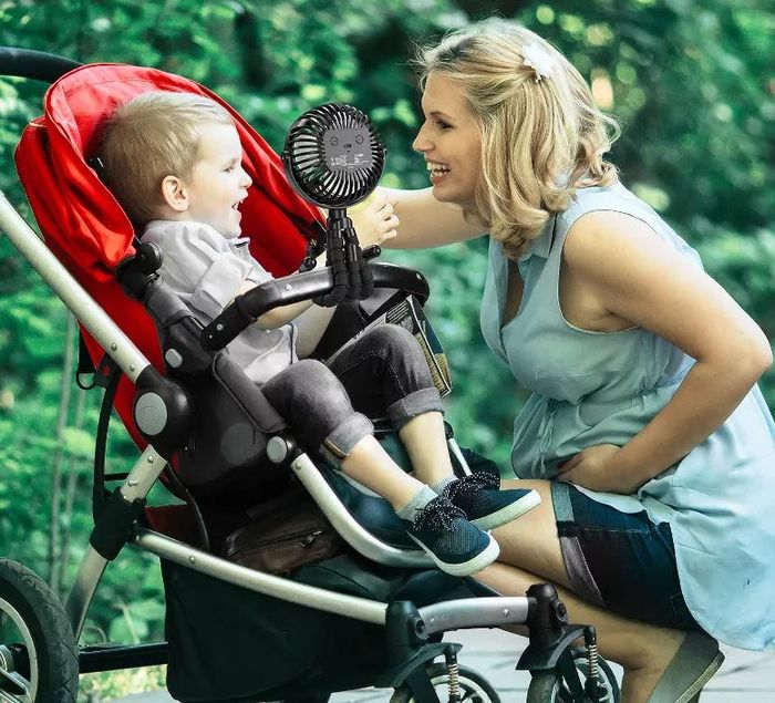 A black fan securely attached to a stroller.