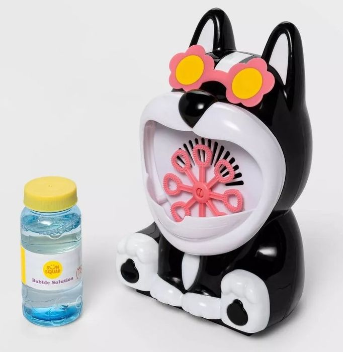 A black and white plastic dog with a bubble maker in its mouth, along with a jar of bubble solution.