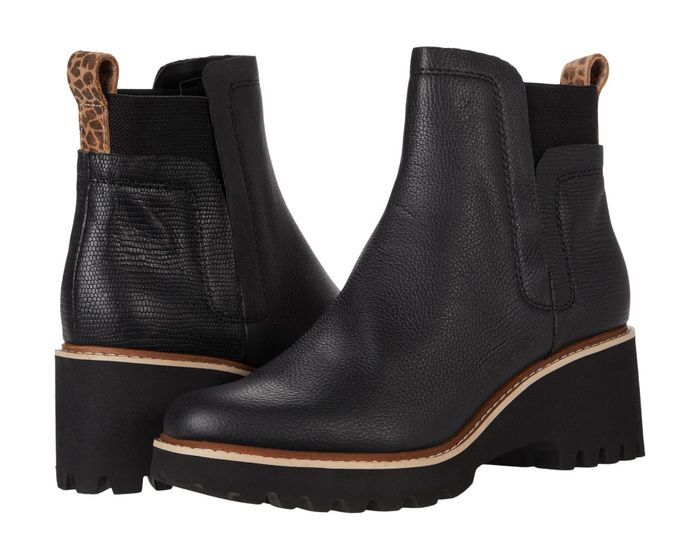 A pair of black ankle boots with chunky soles, featuring leopard-print pull-tabs at the back, displayed at an angle to show both the side and rear details.