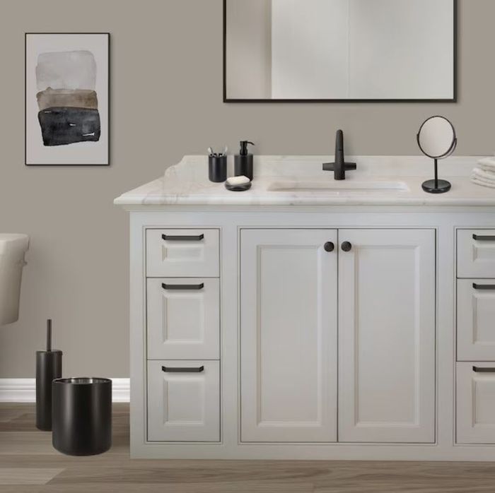 A contemporary bathroom vanity with double doors and ample drawer space, showcasing a black faucet, toiletries, a circular mirror, and minimalist accents.
