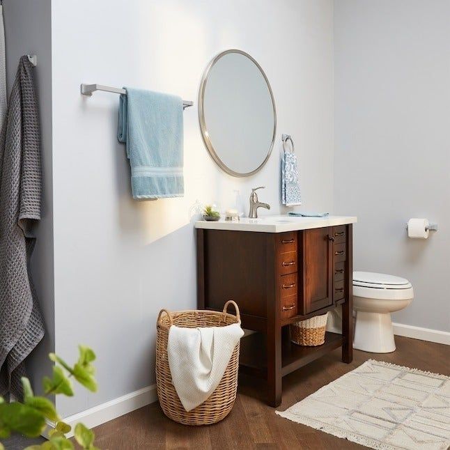 A contemporary bathroom design featuring a mirror, vanity, a wicker basket, and a neatly hung towel on a rack.