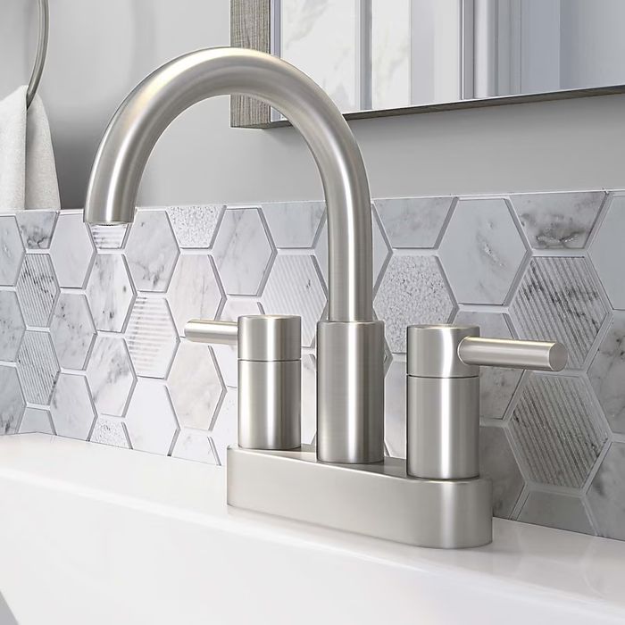 A modern bathroom faucet showcasing a dual-handle design with a gracefully curved spout, beautifully set against a backdrop of hexagonal tile backsplash.
